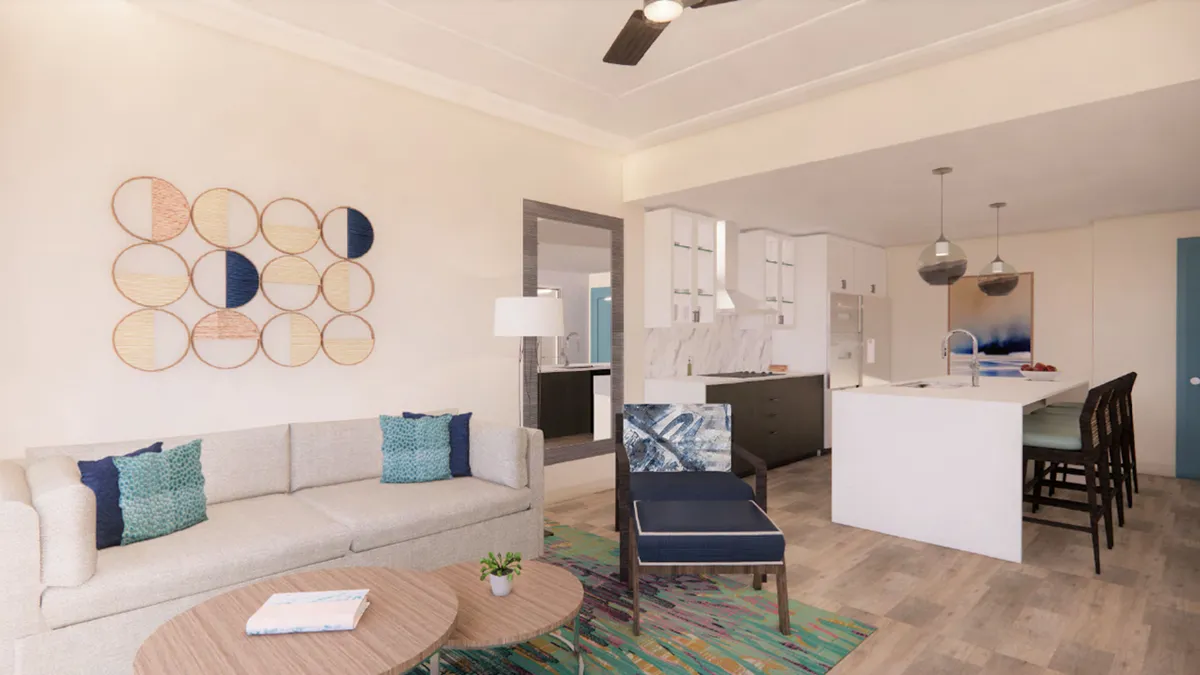 The image showcases a bright and inviting living area with a comfortable sofa adorned with vibrant, colorful pillows, stylish decorative wall art, and a spacious kitchen island, creating an open space perfect for gathering, relaxing, and making memories.